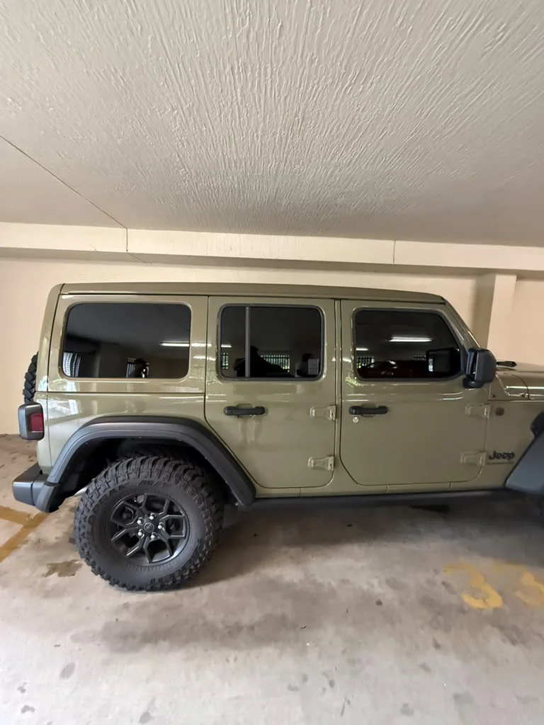 Side view of a green Jeep with tinted windows